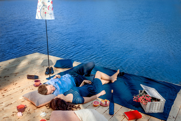pareja tumbada en la terraza cerca del agua
 - Foto, imagen