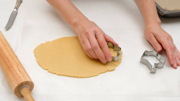 Plätzchenteig und Ausstechformen dicht an dicht auf dem Küchentisch, flach gelegt. Blumenförmige Shortbread Cookies Rezept - Foto, Bild