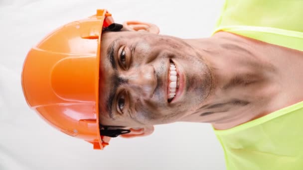 Portrét smíšené závod chlap s špinavou tváří v práci tvrdý klobouk úsměvy sněhobílý úsměv - Záběry, video