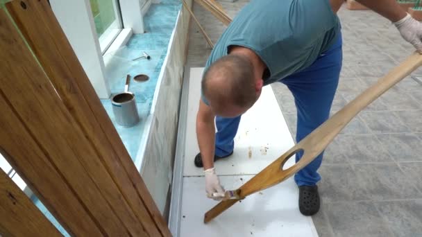 Robotnik polerowanie deski drewnianej lakierem. Guy polerować deskę drewnianą - Materiał filmowy, wideo