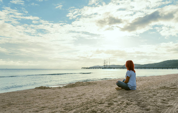 夏の景色バルト海のルゲン島の朝の光の中でビーチに座っている若い女性と. - 写真・画像