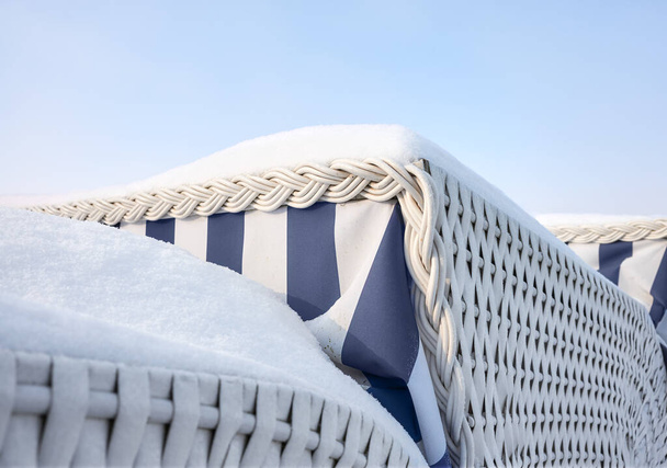 Detailní záběr zastřešených proutěných plážových židlí pokrytých sněhem, selektivní zaměření. - Fotografie, Obrázek