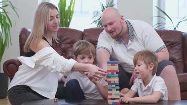 Ευτυχισμένοι γονείς και δύο χαρούμενους γιους που παίζουν στο επιτραπέζιο παιχνίδι, ξύλινος πύργος - Πλάνα, βίντεο