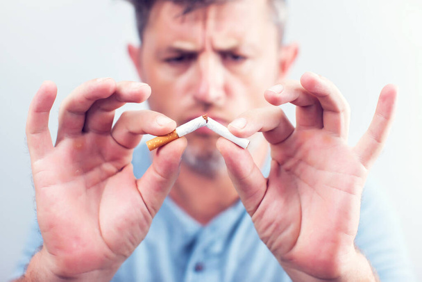 Cigarette étant cassé en deux morceaux par l'homme arrêter de fumer arrêter la dépendance - Photo, image