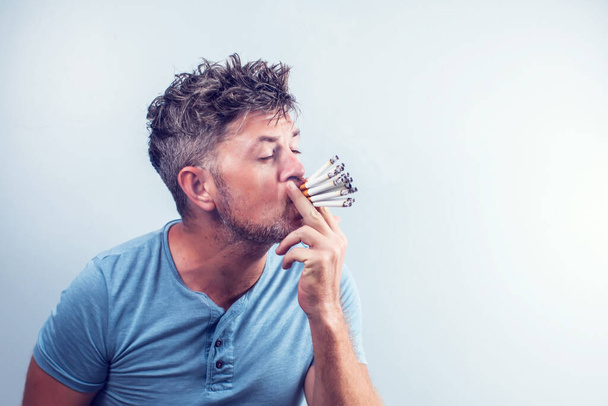 Молодой человек с кучей сигарет во рту - Фото, изображение
