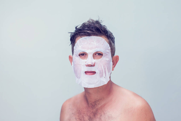 мужчина в косметической маске по уходу за кожей - Фото, изображение