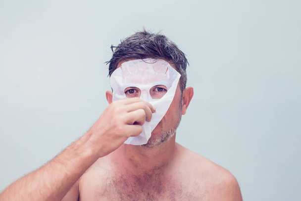 мужчина в косметической маске по уходу за кожей - Фото, изображение