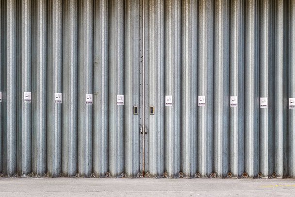 Puertas industriales correderas y plegables con carteles de no fumar, una bahía de carga para camión de reparto en una calle de la ciudad de Londres - Foto, imagen