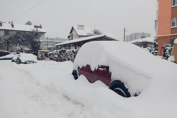 都市の雪の中で雪で覆われた車。冬の吹雪の後、自動車は山に閉じ込められた - 写真・画像
