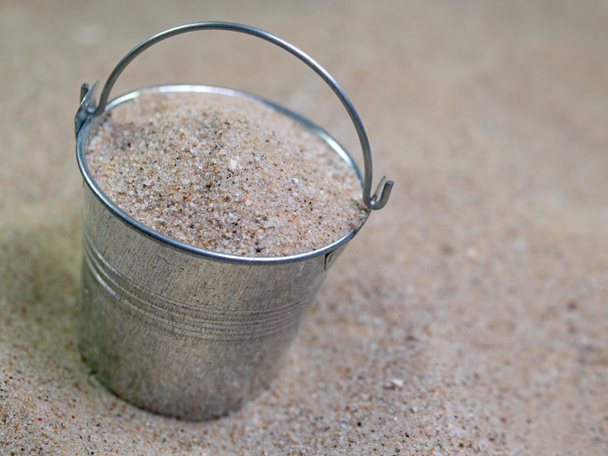 Cubo de zinc lleno de arena de cuarzo en la arena - Foto, imagen