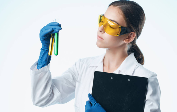 médico mulher em luvas médicas e em um casaco médico branco contém frascos em suas mãos documentos - Foto, Imagem