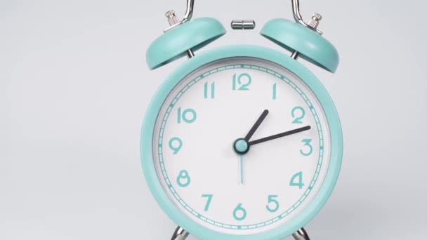 Close up, Time lapse, Short blue alarm clock tells the time of one o'clock.  On the white background. - Filmagem, Vídeo