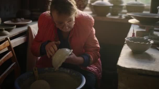 ワークショップで鍋を出す高齢女性。スタジオでシニア女性乾燥ポット - 映像、動画