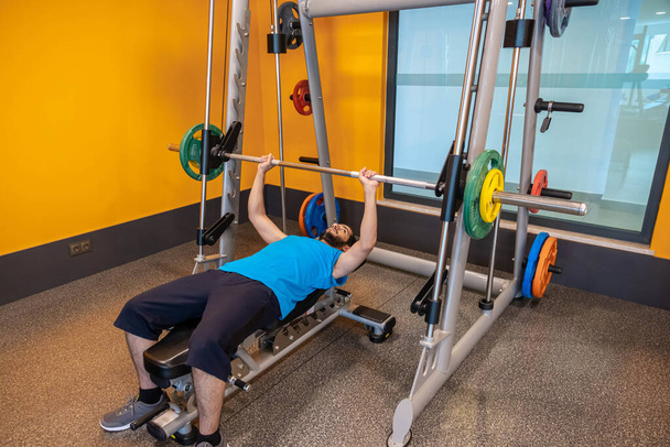Arabischer Mann pumpt seine Muskeln auf der Bank auf, um seine Brustmuskeln im Fitnessstudio aufzubauen - Foto, Bild