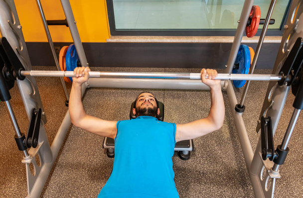 Arabische man pompt zijn spieren op de bank voor het opbouwen van zijn borstspieren in de sportschool - Foto, afbeelding