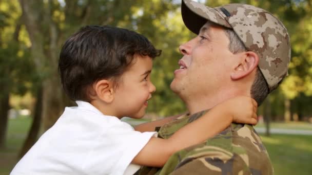 Ευτυχισμένος στρατιωτικός μπαμπάς που κρατάει τον μικρό γιο στην αγκαλιά του - Πλάνα, βίντεο