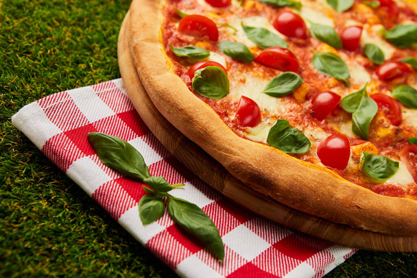 Traditionelle italienische Pizza margarita mit Käse, Tomaten und Basilikum auf grünem Gras Hintergrund - Foto, Bild