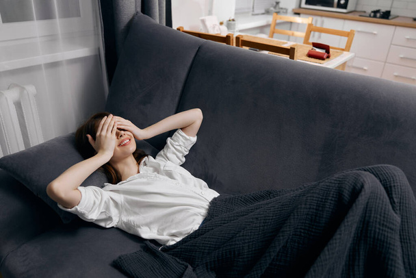 женщина закрыла глаза руками и легла на мягкий диван - Фото, изображение