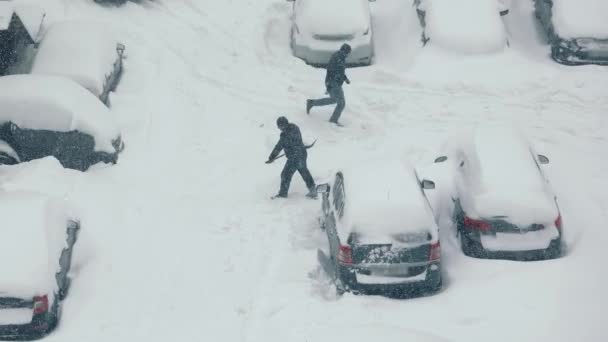 Top näkymä kuin mies tyhjentää auton pysäköity lähelle lunta. Raskas lumisade. - Materiaali, video