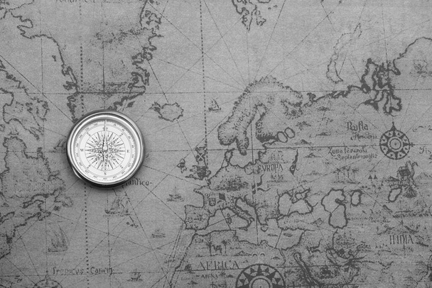 Classic round compass on background of old vintage map of world as symbol of tourism with compass, travel with compass and outdoor activities with compass - Photo, Image