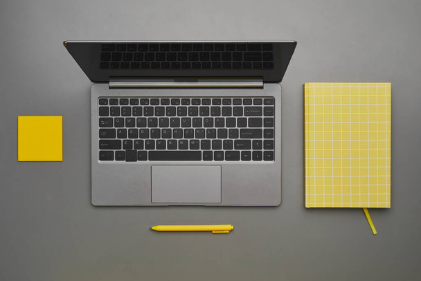 Grafik grau und gelb Hintergrund des Laptops mit Business-Accessoires am Schreibtisch, flache Ansicht von oben nach unten, Kopierraum - Foto, Bild
