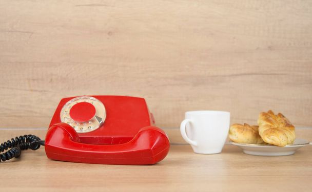 Two bun with poppy seeds with coffee cup and retro rotary phone on wood table. Breakfast. Coffee time - Photo, Image