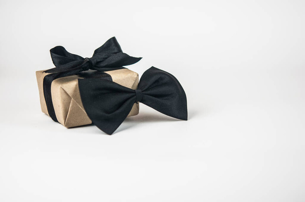 Одна подарочная коробка, завернутая в бумагу с галстуком бабочки на белом фоне. Концепция День отца или День рождения фон. Международная концепция мужского дня. - Фото, изображение