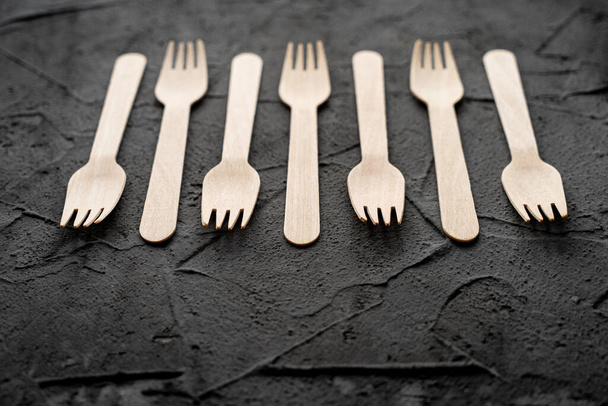 Wooden knife and fork on the black background. Eco friendly zero-waste concept. Top view with space for text Copy space - Photo, Image