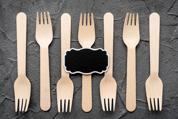 Messer und Gabel aus Holz auf schwarzem Hintergrund. Umweltfreundliches Null-Abfall-Konzept. Draufsicht mit Platz für Text Kopierraum - Foto, Bild