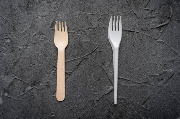 Cuchillo y tenedor de madera sobre fondo negro. Concepto ecológico de cero residuos. Vista superior con espacio para texto Copiar espacio - Foto, imagen