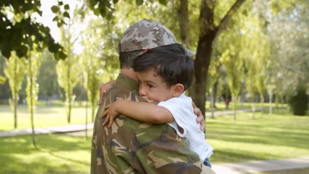 Ευτυχισμένος στρατιωτικός πατέρας που κρατάει τον γιο του στην ύπαιθρο - Πλάνα, βίντεο