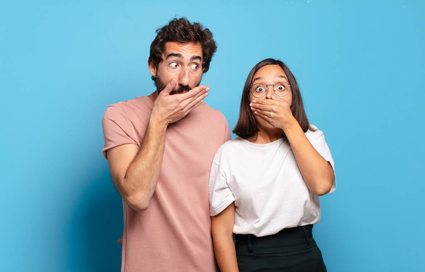 young couple covering mouth with hands with a shocked, surprised expression, keeping a secret or saying oops - Фото, зображення