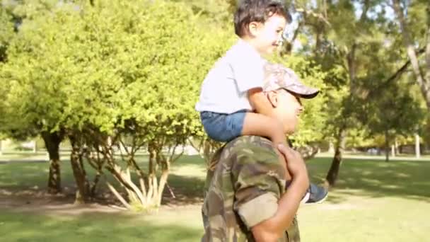 Excited little boy riding dads shoulders in park - Footage, Video