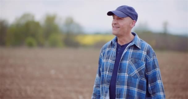 Agricultor exitoso positivo que examina el campo agrícola mientras trabaja en la computadora digital de la tableta. - Metraje, vídeo