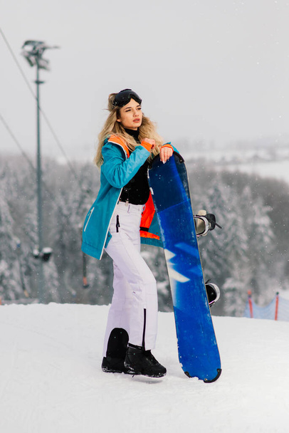 Молода спортивна усміхнена жінка взимку зі сноубордом, окуляри
 - Фото, зображення