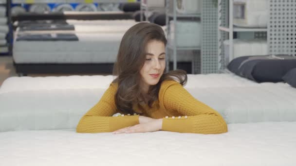 Beautiful happy woman examining orthopedic mattress on sale - Footage, Video