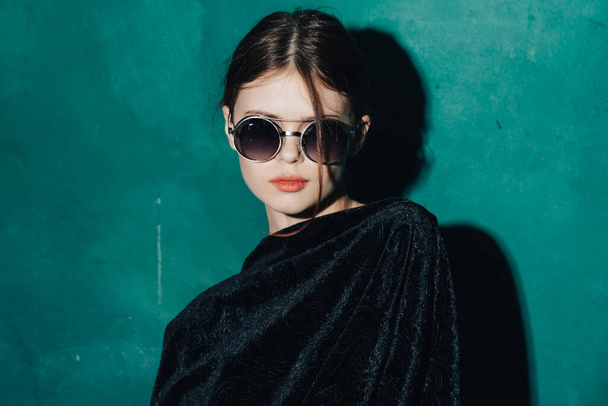 woman in sunglasses on a green background black sweater model close-up - Foto, Imagem
