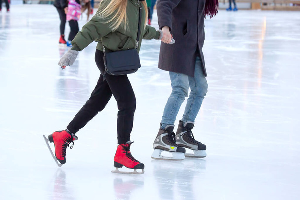 diferentes personas están patinando activamente en una pista de hielo. pasatiempos y ocio. deportes de invierno - Foto, Imagen