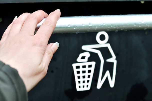  Tirar basura a mano en un contenedor de reciclaje vacío.Un bote de basura inteligente moderno en la calle. Recogida de residuos en Europa para su posterior eliminación.Concepto de protección del medio ambiente - Foto, Imagen