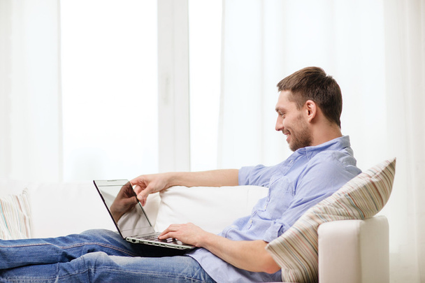Smiling man working with laptop at home - Φωτογραφία, εικόνα