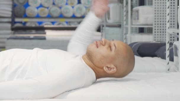 Homem africano feliz deitado no colchão ortopédico na loja de móveis - Filmagem, Vídeo