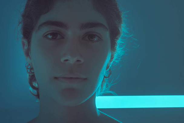retrato menina no fundo da parede azul com luzes brilhantes néon. Retrato de néon de uma menina. - Foto, Imagem