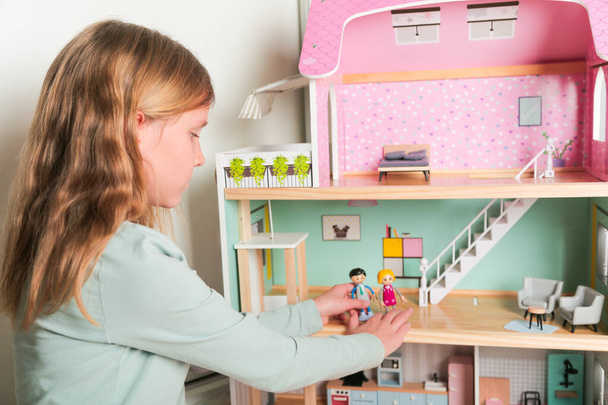 Ευτυχισμένο κορίτσι παίζει με κούκλα σπίτι και κούκλες. Ευτυχισμένο παιδί. - Φωτογραφία, εικόνα
