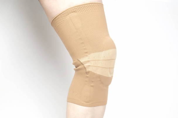 白い背景で人間の足の膝を固定する包帯。医学とスポーツ。手足の怪我治療 - 写真・画像