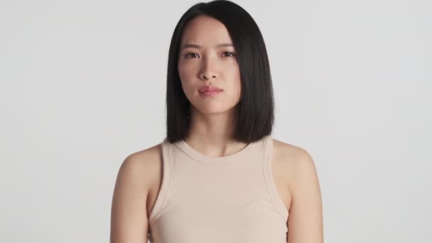 Mujer asiática joven mirando con confianza agitando la cabeza ningún gesto en la cámara aislada sobre fondo blanco. Expresión en desacuerdo - Metraje, vídeo