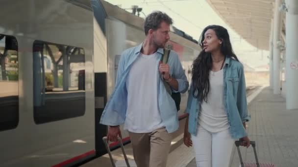 ζευγάρι ταξιδιωτών περπατά για να εκπαιδεύσει, κυλιόμενη βαλίτσα - Πλάνα, βίντεο