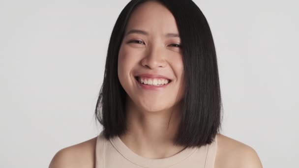 Портрет привабливої усміхненої азіатської дівчини, яка виглядає задоволеною зображенням на фотоапараті, ізольованим на білому тлі. Концепція виразу обличчя - Кадри, відео