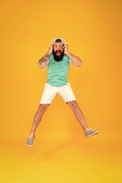 In the air. summer vacation party. brutal hipster jump high. his favorite song. mature dj full of energy. feel freedom. celebrating success. bearded man listen music. happy guy wear headphones - Фото, зображення