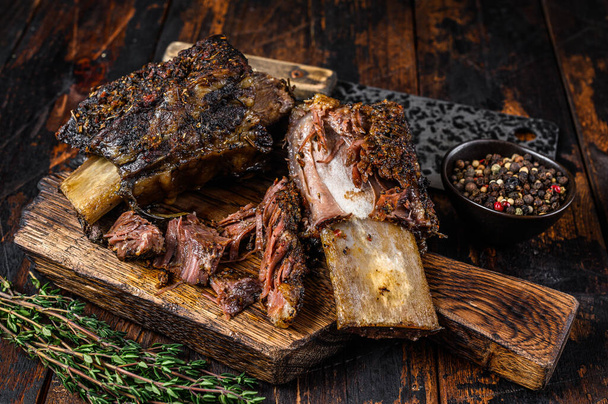 Grill rövid chuck marhahús bordák fűszerekkel és húsbárddal. Sötét fa háttér. Felülnézet - Fotó, kép