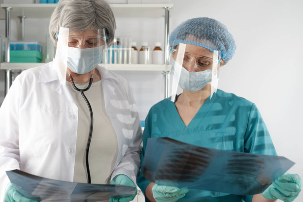 Γιατρός ηλικιωμένη γυναίκα με λευκό παλτό και γυναίκα παραϊατρικό εξετάσει ακτινογραφία στο νοσοκομείο - Φωτογραφία, εικόνα
